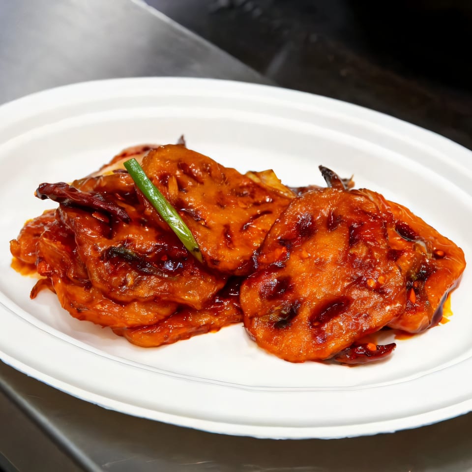 Fat Panda's spicy lotus root dish, glistening with a rich, dark red sauce and garnished with green onion.