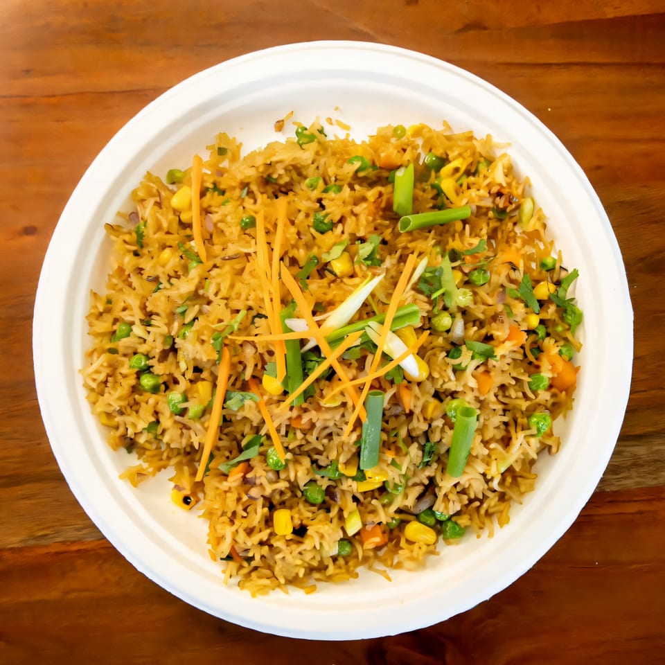 Fat Panda's vegetable fried rice, garnished with shredded carrots and green onions, in a white bowl.