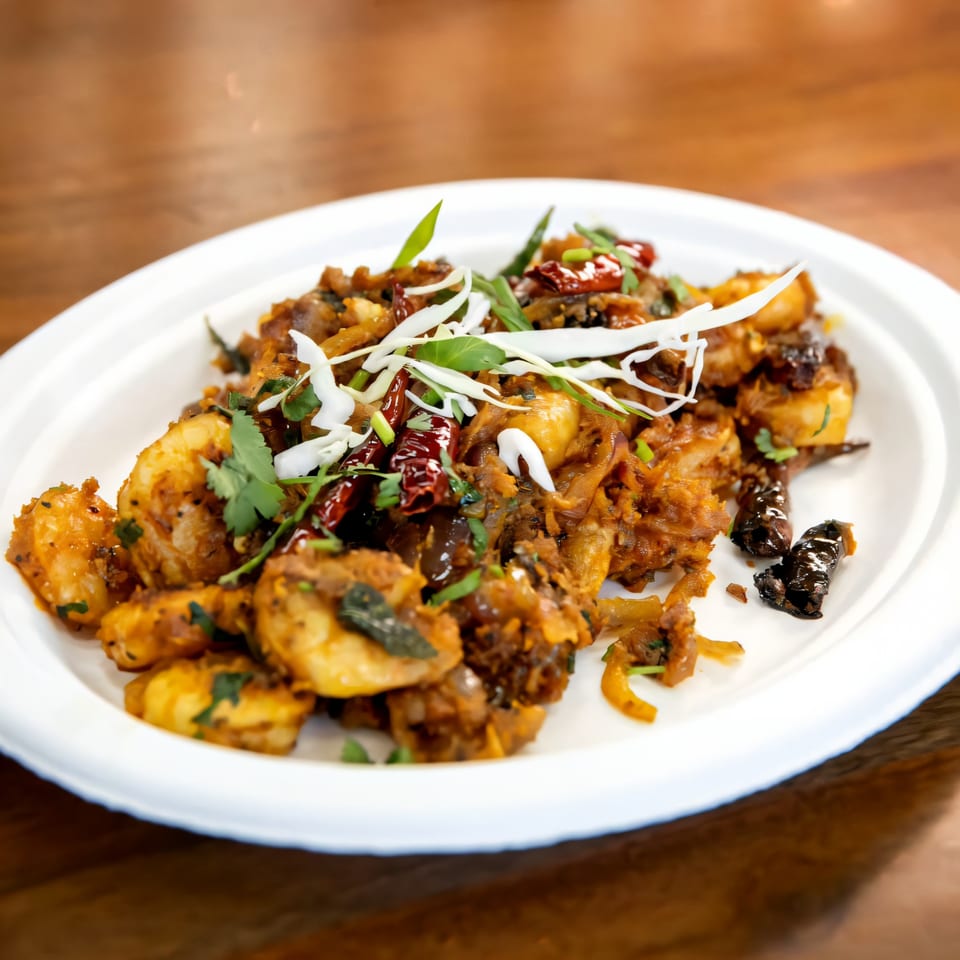 Fat Panda's spicy Asian-fusion shrimp dish, garnished with fresh herbs and dried chilies on a white plate.