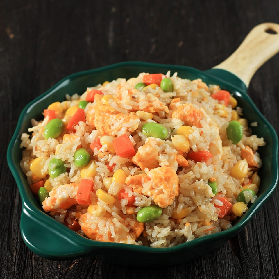 Fat Panda's fried rice with scrambled egg, carrots, corn, and edamame in a green pan.